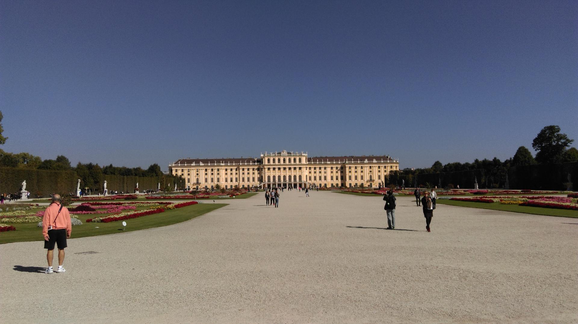 Zámek Schönbrunn ve Vídni s parterovou zahradou a procházejícími se návštěvníky